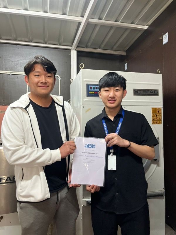 Norden Machineries representative with aBit team holding the signed aBitPOS agreement