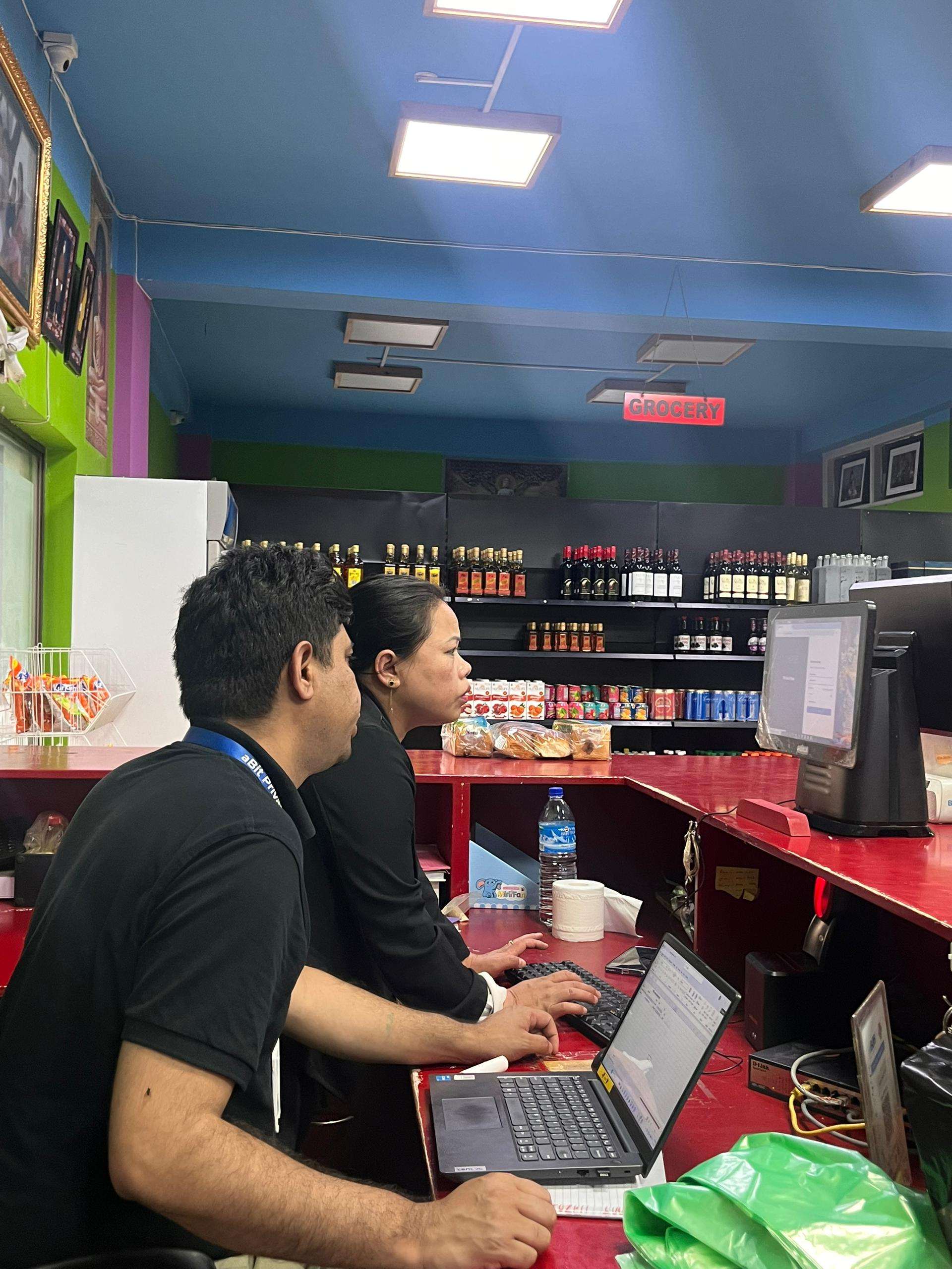 aBit consultant training the PR Meat Shop team on aBitPOS at the counter beside the grocery shelves