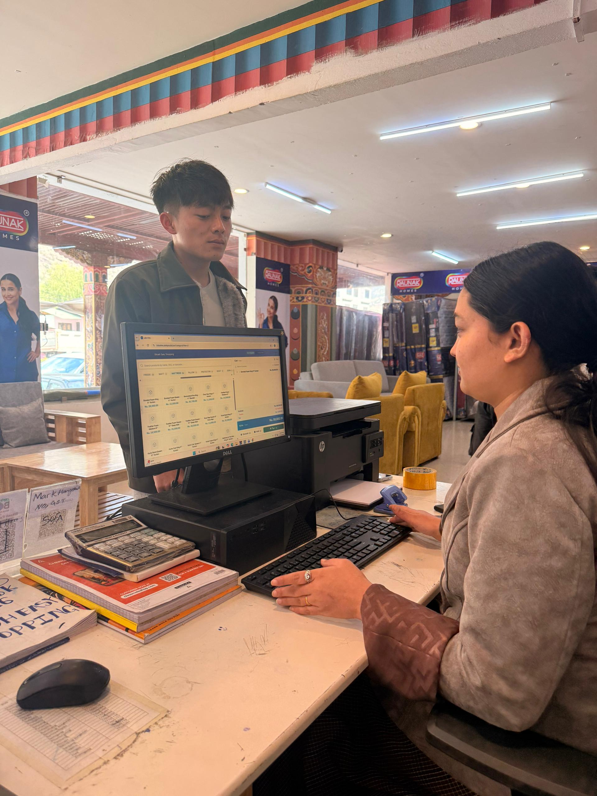 Bikash Easy Shopping staff using aBitPOS dashboard at the counter with showroom in background